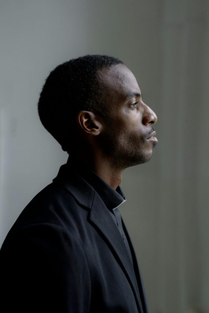Profile portrait of a man in clerical clothing, thoughtful expression, side view indoors.